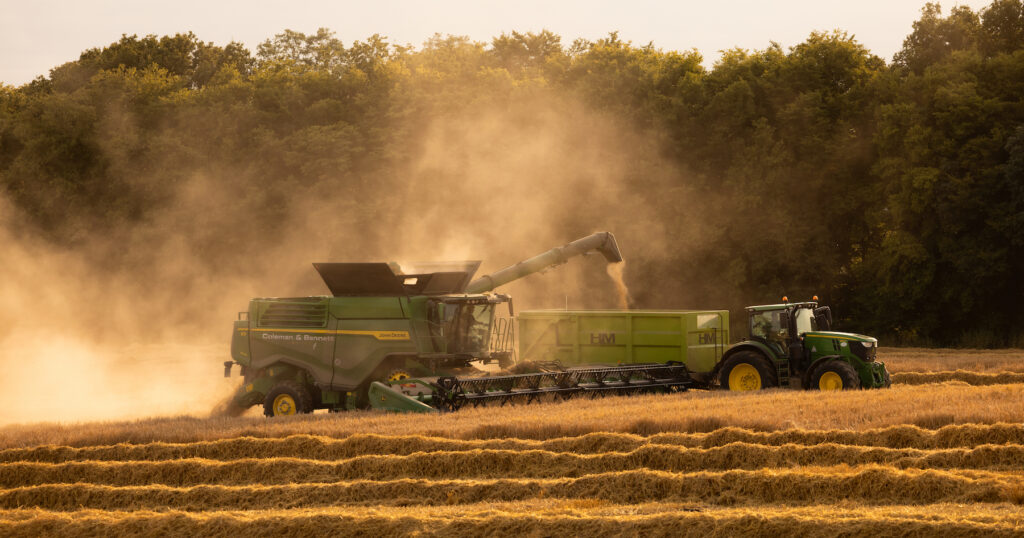 combine harvester harvesting barley in British field as sun sets